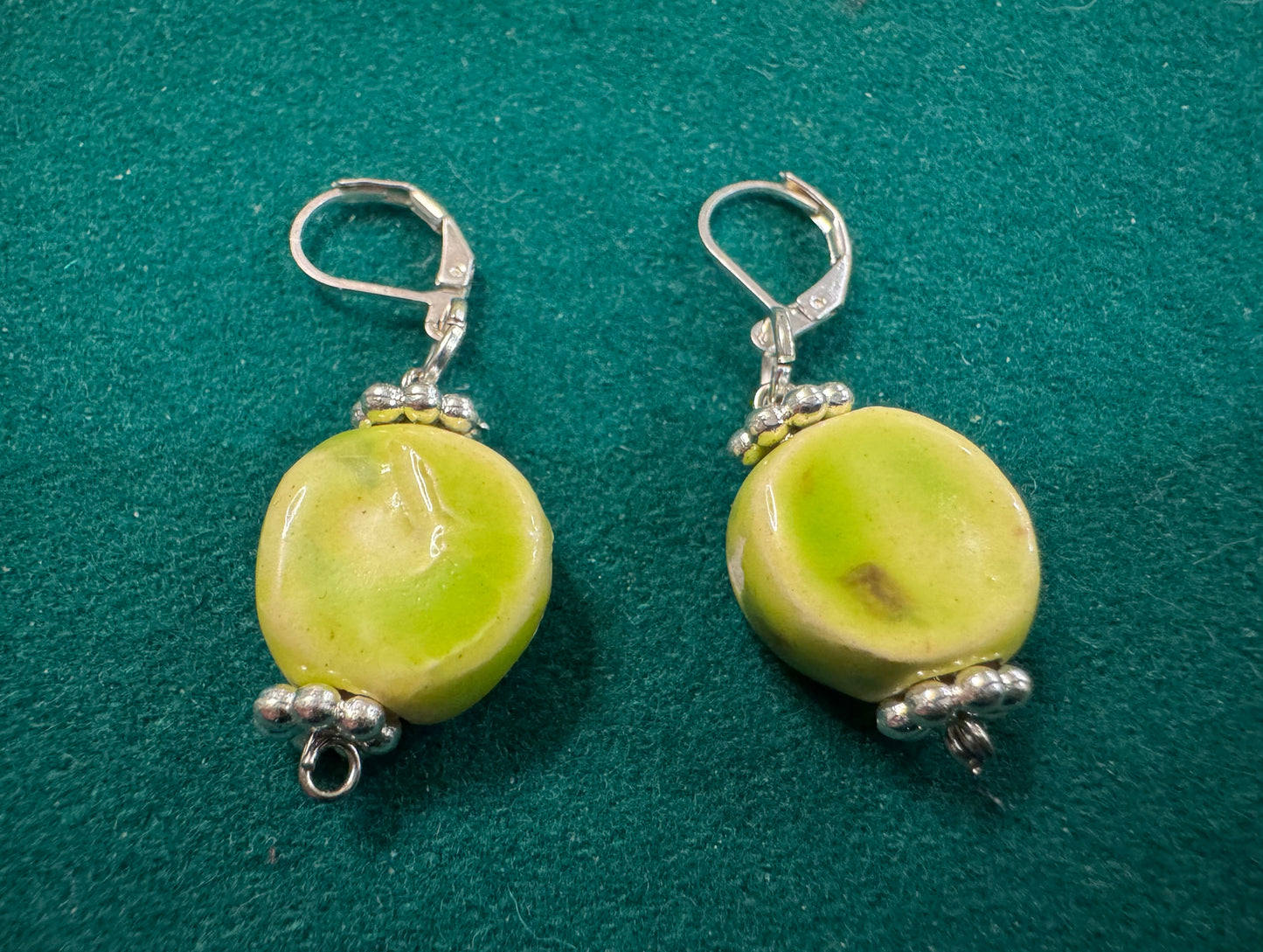 One-of-a-kind hand built ceramic circle shaped earrings that are hand glazed soft green by Las Vegas artist JanDWolf. Art you can wear that no one else has. Be original. Be unique. Be you. 
 Soft Green Circle Earrings